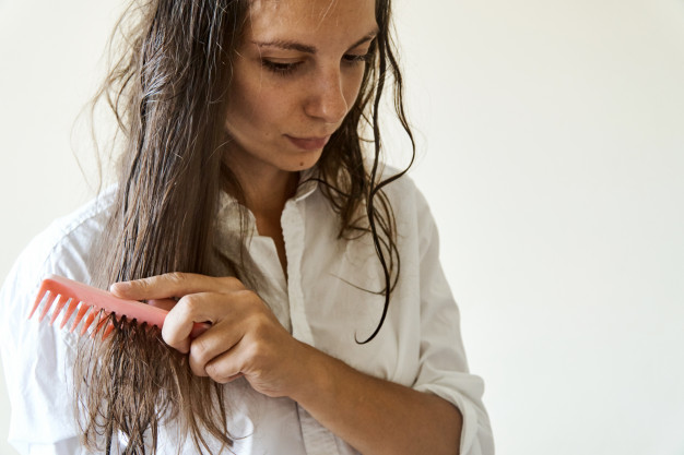 mujer se aplica productos para el cabello con el peine