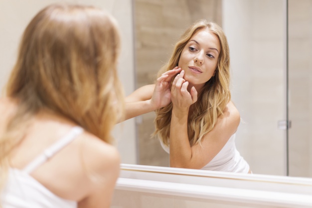 Mujer rubia tiene problemas con la piel de la cara