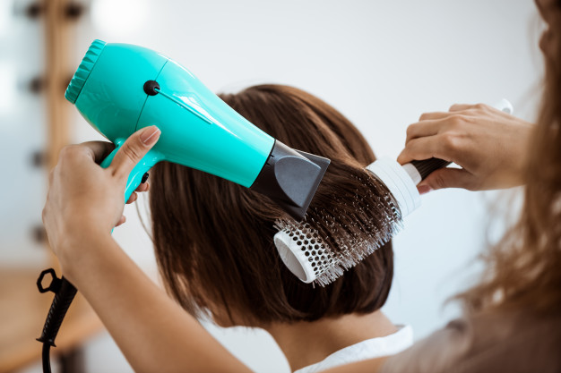 mujer utiliza secadora en su pelo